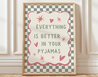 May include: A framed print with the text "EVERYTHING IS BETTER IN YOUR PYJAMAS". The text is in a white, wavy-edged shape, with pink accents and decorative stars and hearts, set against a green and white checkered background.
