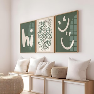Könnte beinhalten: Drei gerahmte Kunstdrucke mit modernem Design. Der erste Druck zeigt "hi" in Weiß auf dunkelgrünem Hintergrund. Der zweite Druck zeigt eine Ansammlung grüner Herzen auf beigem Hintergrund. Der dritte Druck hat zwei weiße Smiley-Gesichter auf dunkelgrünem Hintergrund.