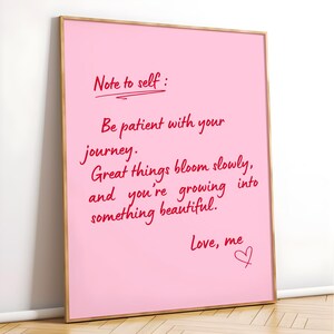 May include: A framed pink print with handwritten red text. The text reads "Note to self: Be patient with your journey. Great things bloom slowly, and you're growing into something beautiful. Love, me."