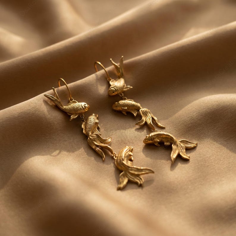 May include: Gold-coloured fish earrings. Each earring has a hook and a series of detailed fish charms, creating a dangling effect. The fish have textured scales and flowing fins, adding to their realistic appearance.