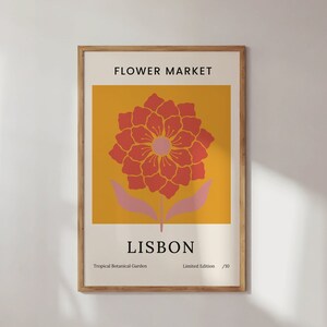 May include: A framed poster with a yellow background and a stylised red flower with pink leaves. The poster says "FLOWER MARKET" at the top and "LISBON" at the bottom. The text "Tropical Botanical Garden" and "Limited Edition /10" are also included.