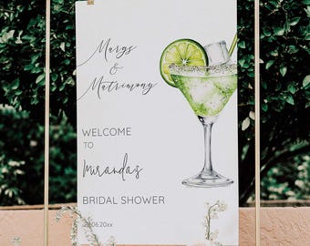 May include: White sign with black text that reads "Margs & Matrimony" and "Welcome to Miranda's Bridal Shower" with a watercolor illustration of a margarita with a lime wedge and a straw.