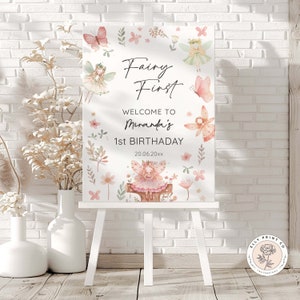 Puede incluir: Un cartel blanco con una ilustración de acuarela de un hada con alas rosadas y una corona de flores. El cartel dice "Fairy First" y "Bienvenido a Miranda's 1er cumpleaños 20.06.20xx".