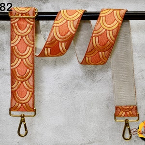 May include: A peach-colored adjustable strap with a gold-colored buckle and a geometric pattern. The strap is hanging from a black bar. The text "ST182" is visible in the top left corner of the image.