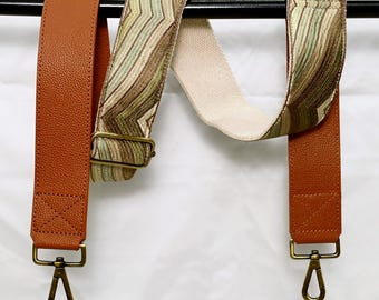 May include: Two brown leather straps with gold metal clasps. One strap has a green and brown patterned fabric strap attached. The straps are hanging from a black bar. The text "ST-634" is visible at the top of the image.