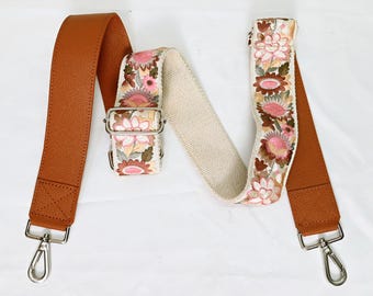 May include: A brown leather and white canvas adjustable strap with floral embroidery and silver hardware. The strap is approximately 48 inches long. ST-632