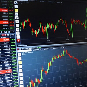 May include: A computer screen displaying stock market data with multiple charts and numerical information. The charts show green and red lines, indicating market fluctuations. Various financial data is visible.