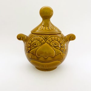 May include: A brown ceramic onion jar with a crying face and the word "Onion" on the lid.