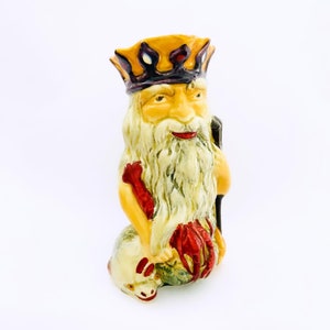 May include: A ceramic figurine of a king with a yellow and purple crown, a long white beard, and a red and white staff. The king is sitting on a green and white sea creature.