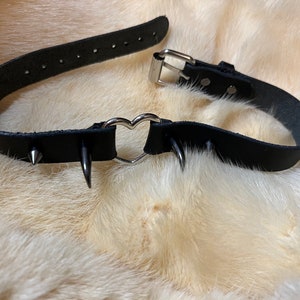 May include: Black leather choker with silver heart-shaped hardware and silver spikes.