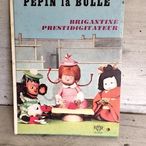 Puede incluir: Libro infantil vintage titulado "Pépin la Bulle" con ilustraciones de tres personajes de dibujos animados. La portada presenta un fondo azul claro con el título en letras negras en negrita y las palabras "Brigantine" y "Prestidigitateur" en rosa.