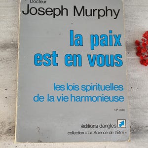 May include: A gray book cover with the title "la paix est en vous" by Joseph Murphy. The book is part of the "La Science de l'Étre" collection and is the 12th edition.