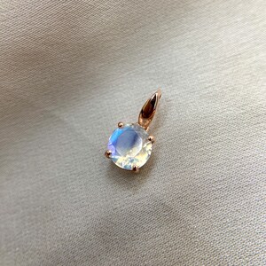 May include: A rose gold pendant featuring a round iridescent gemstone.