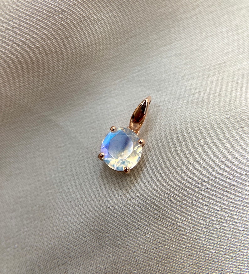 May include: A rose gold pendant featuring a round iridescent gemstone.