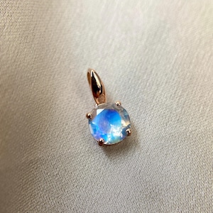 May include: A rose gold pendant featuring a round iridescent moonstone.