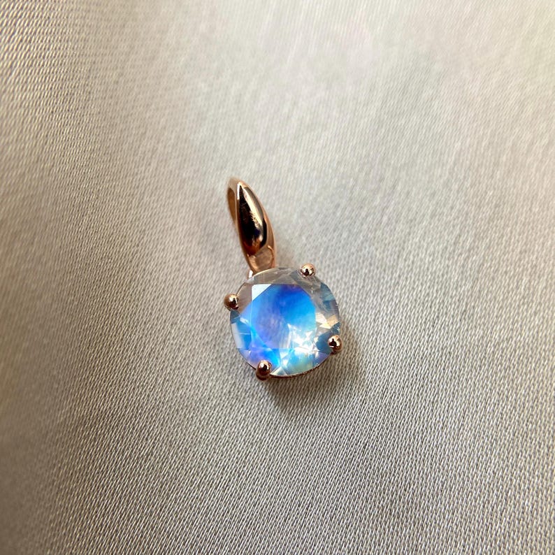 May include: A rose gold pendant featuring a round iridescent moonstone.
