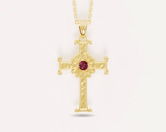 Könnte beinhalten: Ein goldener Kreuzanhänger mit einem roten Edelstein in der Mitte. Das Kreuz hat ein detailliertes, verziertes Design.