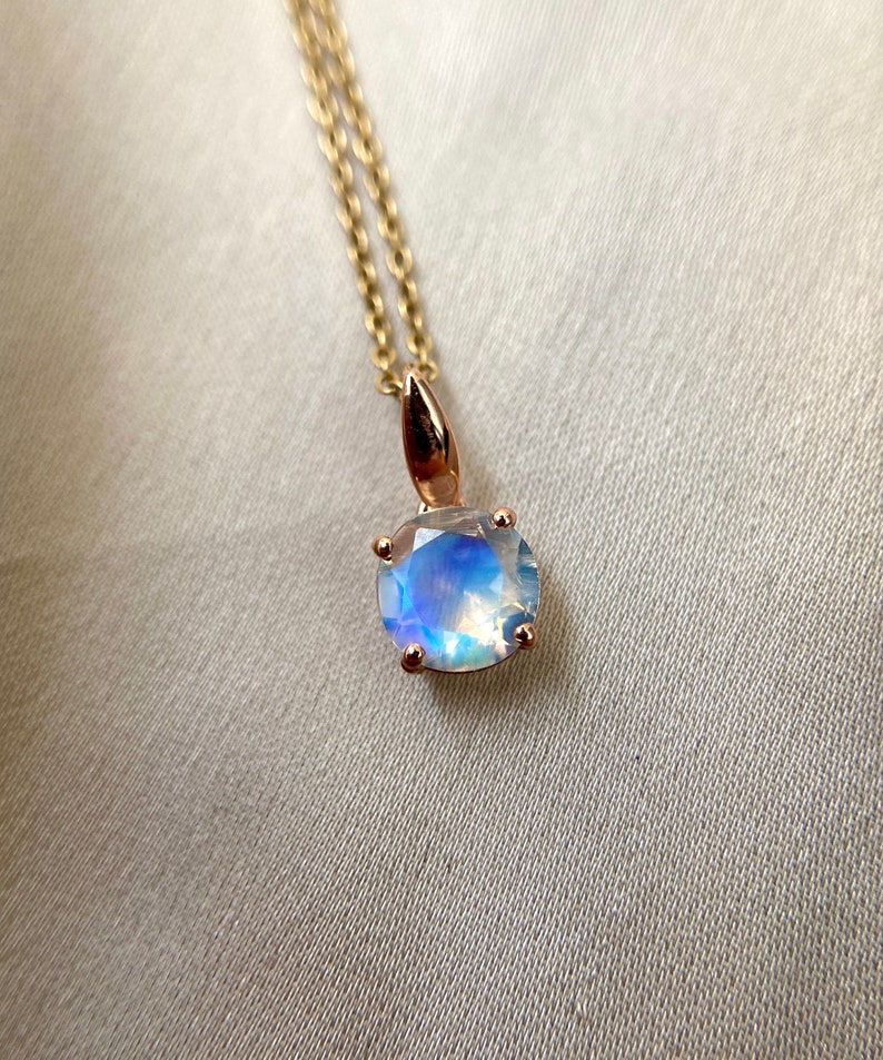 May include: A delicate gold chain necklace with a round iridescent moonstone pendant.