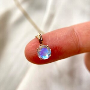 May include: A gold chain necklace with a round iridescent moonstone pendant.
