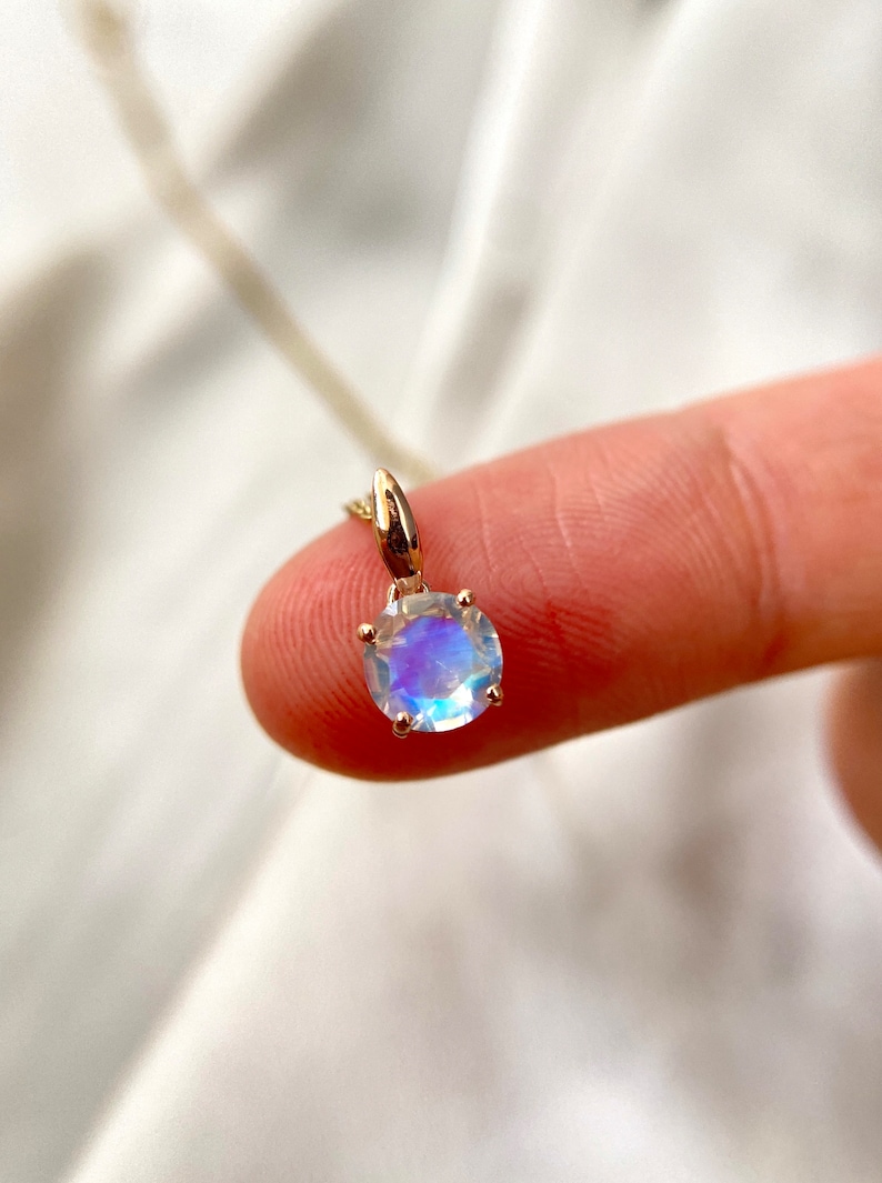 May include: A gold chain necklace with a round iridescent moonstone pendant.