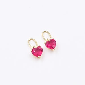 May include: A pair of gold heart-shaped earrings with red gemstone accents.