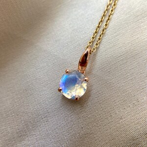 May include: A delicate gold necklace with a round iridescent moonstone pendant.