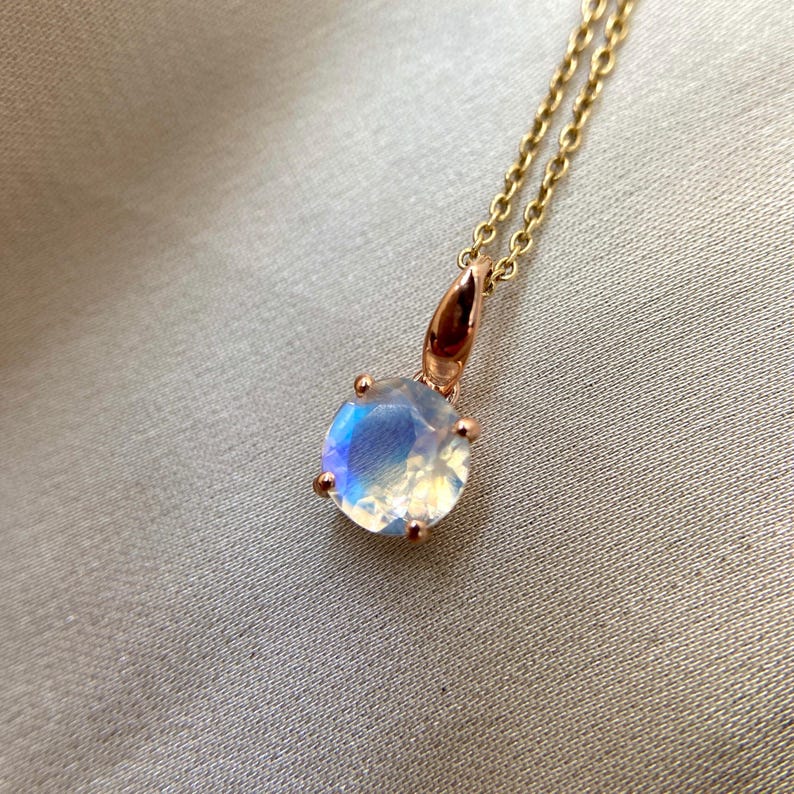 May include: A delicate gold necklace with a round iridescent moonstone pendant.