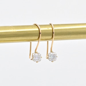 May include: A pair of gold dangle earrings with square-shaped clear gemstones.