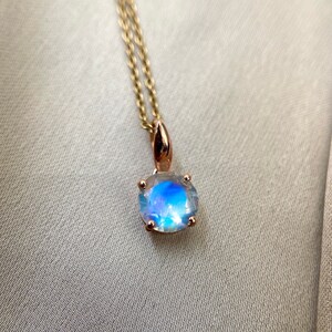 May include: A gold chain necklace with a round iridescent moonstone pendant.