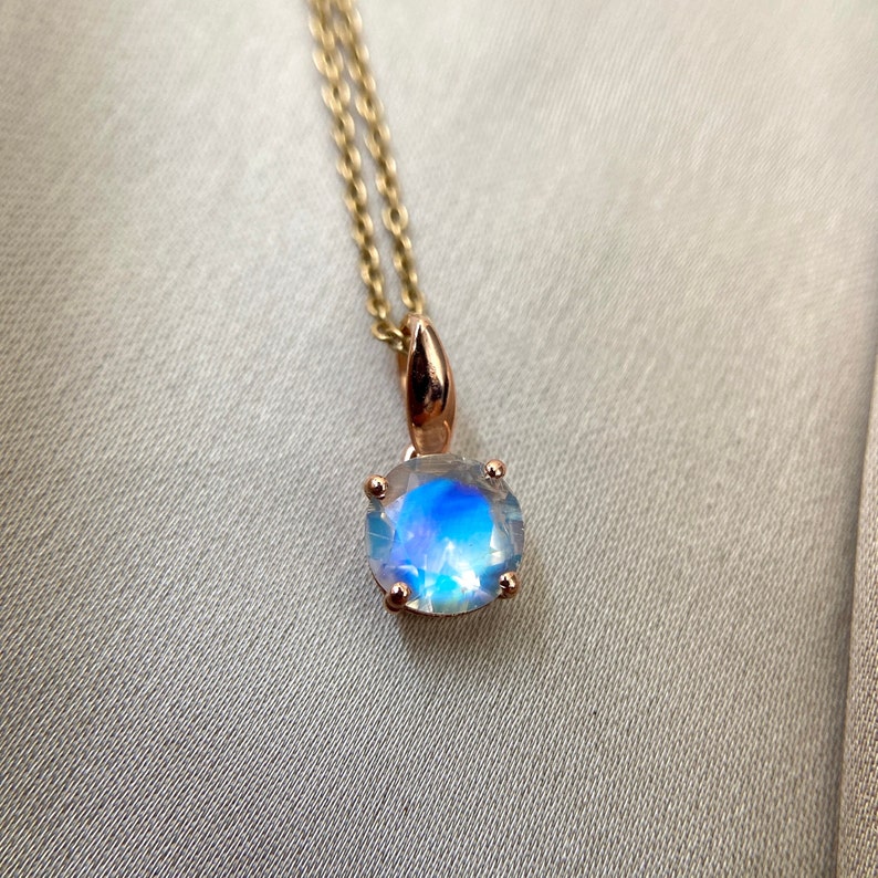 May include: A gold chain necklace with a round iridescent moonstone pendant.