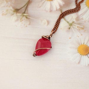 Peut inclure: Un collier en chaîne de cuivre avec un pendentif en pierre rouge enveloppé de fil de cuivre.