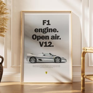 May include: Framed poster featuring a silver sports car with the text "F1 engine. Open air. V12." The car has a sleek design with visible wheels and a low profile. The Ferrari logo is at the bottom.