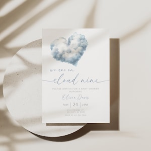 May include: A baby shower invitation featuring a blue cloud heart design. The text says "we are on cloud nine" and includes event details: date, time, and the name of the person being honored. The invitation is on a white background.