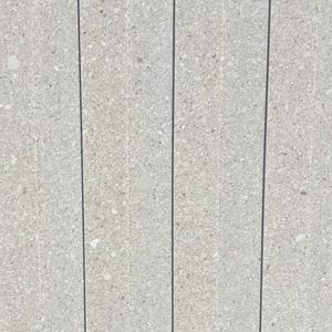 Könnte beinhalten: Nahaufnahme einer hellgrauen, gesprenkelten Steinoberfläche. Die Oberfläche ist in vertikale Paneele mit dunkelgrauen Linien unterteilt. Der Stein hat ein strukturiertes Aussehen mit kleinen, verschiedenfarbigen Flecken.