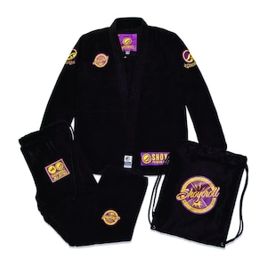 Può includere: Un completo uniforme nero per arti marziali, composto da giacca, pantaloni e sacca con coulisse. L'uniforme presenta toppe ricamate con dettagli oro e viola. Il marchio "Shoyoroll" è visibile sulla sacca e sulle toppe.