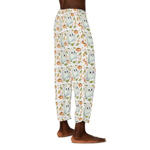 Puede incluir: Pantalón de pijama blanco con un patrón de fantasmas y calabazas. El pantalón tiene una cintura elástica y un ajuste holgado.