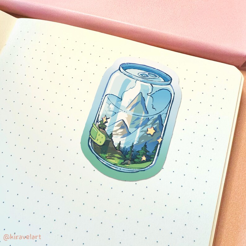 Op de afbeelding: Een sticker van een blikje met een berglandschap erin. Het blikje is blauw en wit met een groen deksel. Het berglandschap is een blauwe berg met een groen bos aan de voet. Er zijn gele sterren verspreid over de sc&egrave;ne.