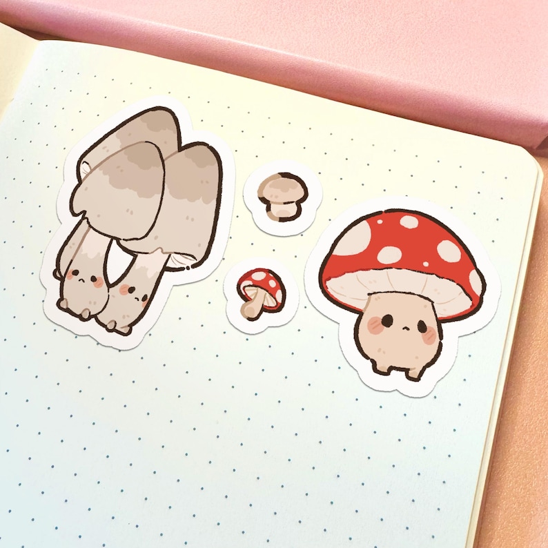 May include: A set of four die-cut stickers featuring anthropomorphic mushrooms. One large cluster of beige mushrooms, two tiny individual mushrooms, and one large red-capped mushroom with white spots, all with simple faces and pink cheeks.