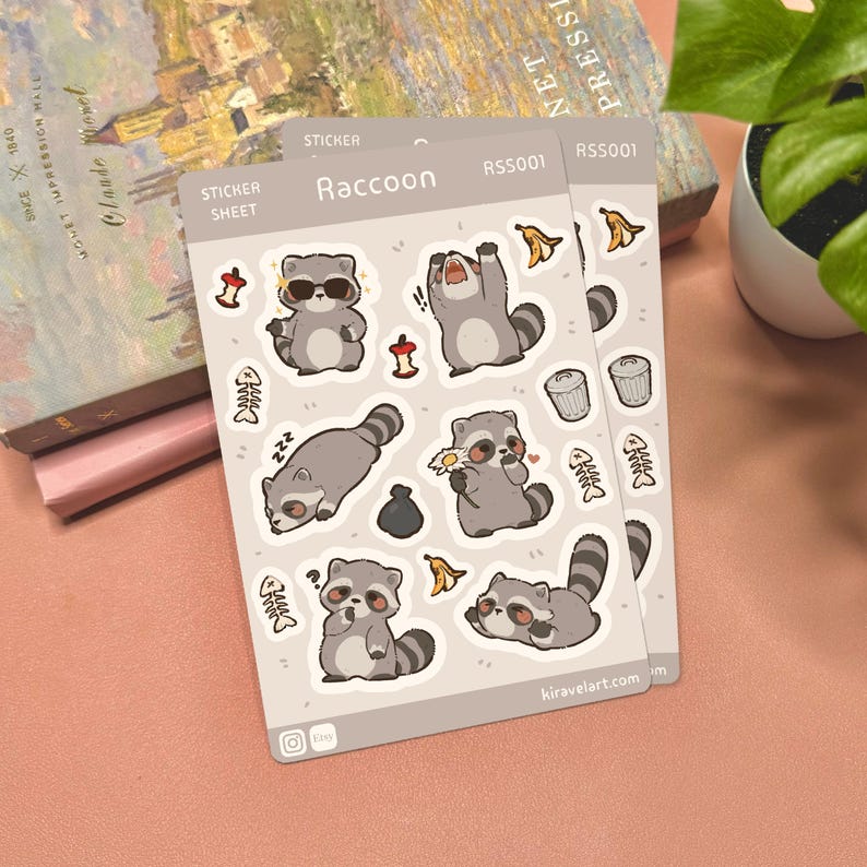 May include: A light beige sticker sheet titled Raccoon RSS001 featuring various cartoon raccoon illustrations, including one wearing sunglasses, one yawning, one holding a flower, and one sleeping, alongside small icons of fish bones and trash.