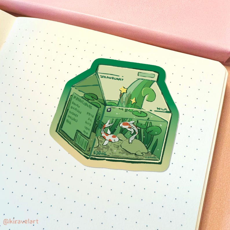 Pode incluir: Um adesivo verde e branco de uma caixa de leite com dois peixes laranja e brancos nadando dentro. A caixa tem a palavra "Strawberry" impressa e um design de onda verde. Os peixes nadam em um tanque com plantas verdes e uma rocha.