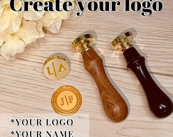 Peut inclure: Deux tampons de sceau en cire dorés avec des manches en bois. Un manche est en bois brun et l'autre en bois noir. Les tampons sont gravés avec les initiales "J/F" et "L/A". Le texte "Create your logo", "*YOUR LOGO", "*YOUR NAME", et "*YOUR DESIGN" est visible sur la surface en bois.