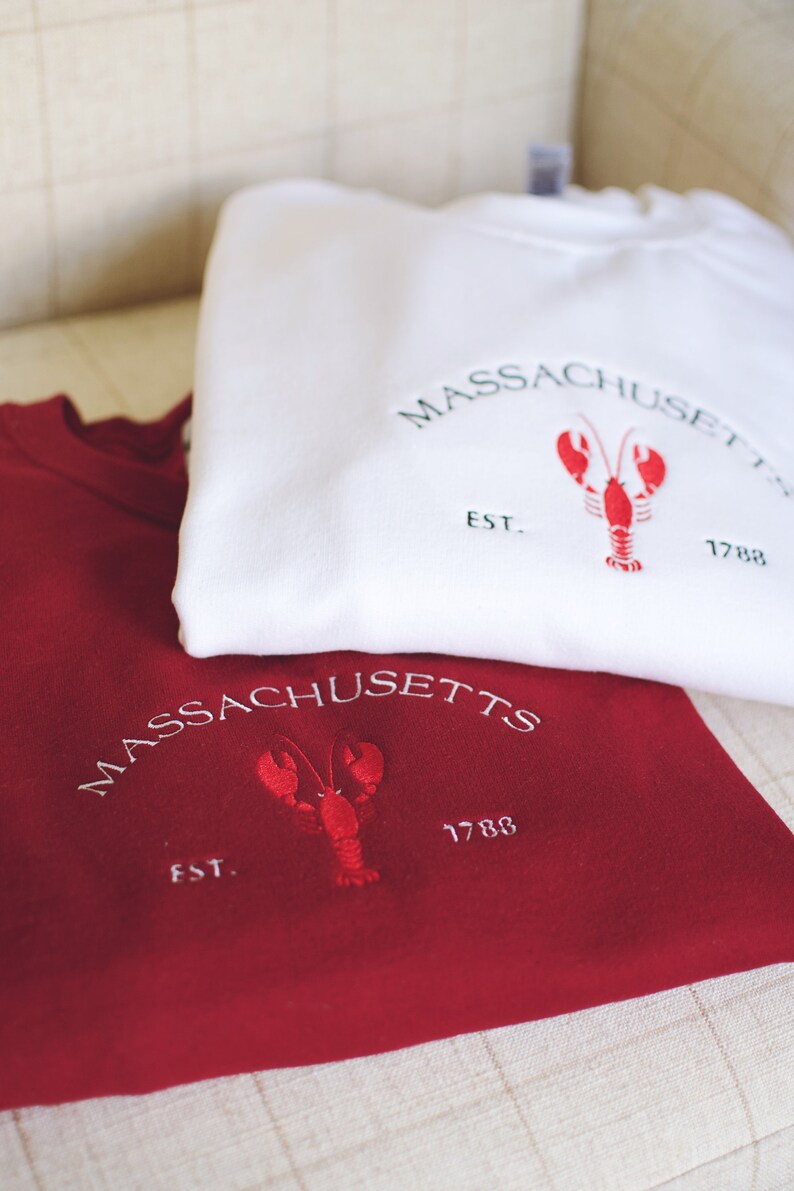 May include: Two sweatshirts, one white and one red, with an embroidered lobster and the text "MASSACHUSETTS EST. 1788".