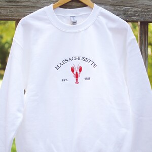 May include: White sweatshirt with a red lobster graphic and the text "MASSACHUSETTS EST. 1788"