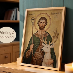 May include: Framed artwork featuring a religious figure with a halo, holding a staff and accompanied by a white deer. The artwork is in a wooden frame and has the words "Saint Hubert of Liege" at the top.