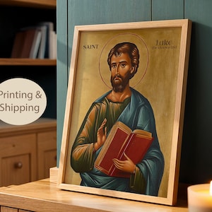 May include: A framed religious icon print featuring Saint Luke the Evangelist holding a red book. The figure has a beard, a halo, and wears a blue and green robe. The text SAINT LUKE THE EVANGELIST is printed in the upper section of the artwork.