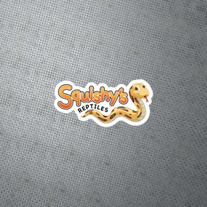 Op de afbeelding: Een witte sticker met een cartoon slang en de tekst "Squishy's Reptiles" in oranje en gele letters.