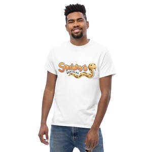 Pode incluir: Camiseta branca com uma cobra de desenho animado e o texto "Squishy's Reptiles" em laranja e marrom.