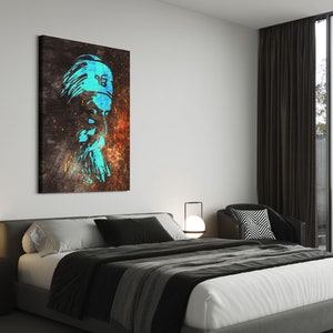 May include: A blue and white abstract portrait of a person wearing a turban with a symbol on it, printed on a canvas. The canvas is hanging on a white wall in a modern bedroom with a bed, bedside table, and lamp.