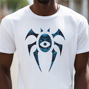 Peut inclure: T-shirt blanc avec un motif bleu et noir d'une araignée stylisée avec des crânes et un œil au centre.
