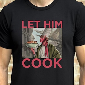 May include: Black t-shirt with the text "LET HIM COOK" in pink. The shirt features a graphic of a chef holding a platter of food. The chef is wearing a white hat, red scarf, and green jacket.